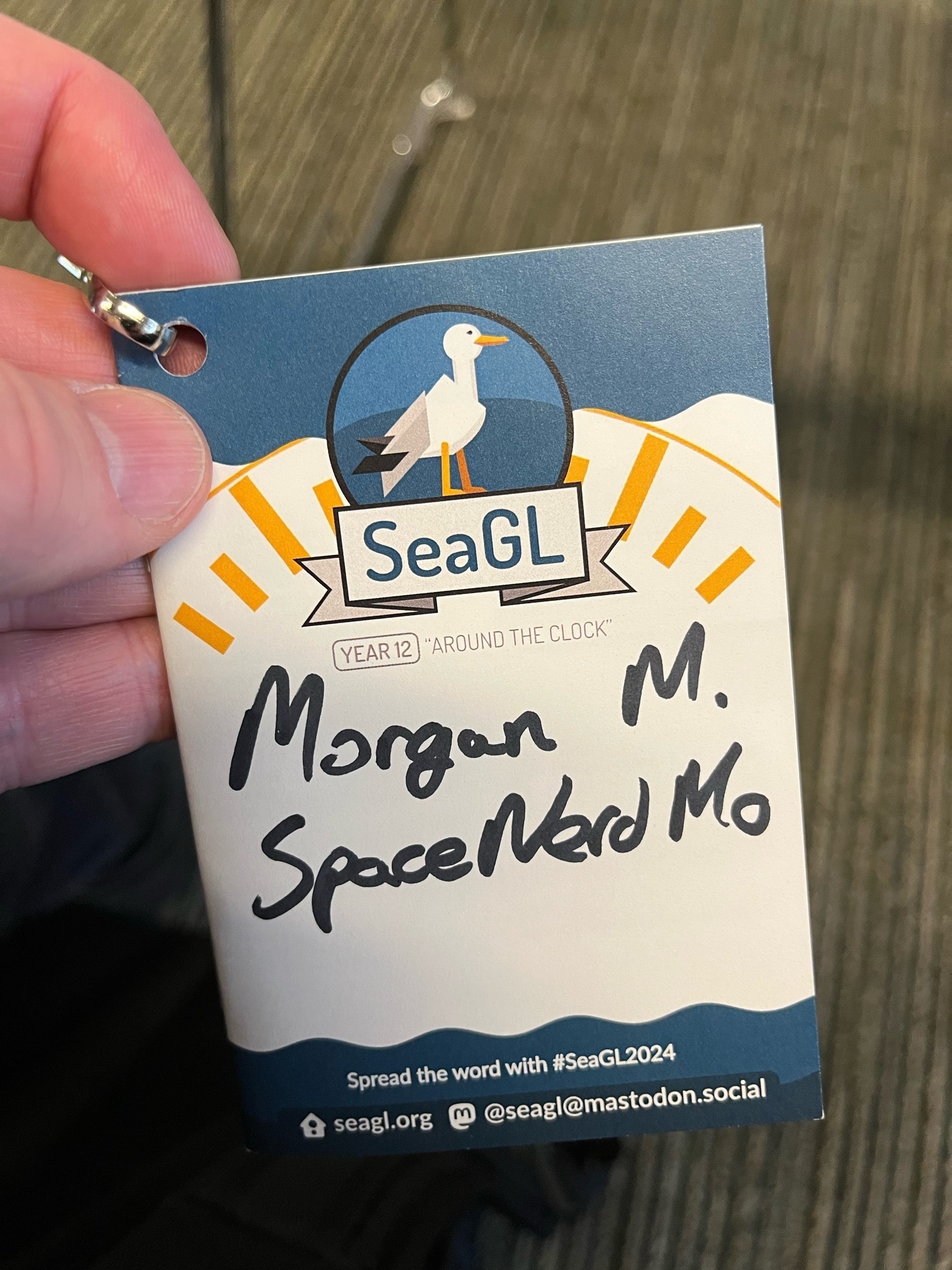 Holding an attendee badge for SeaGL