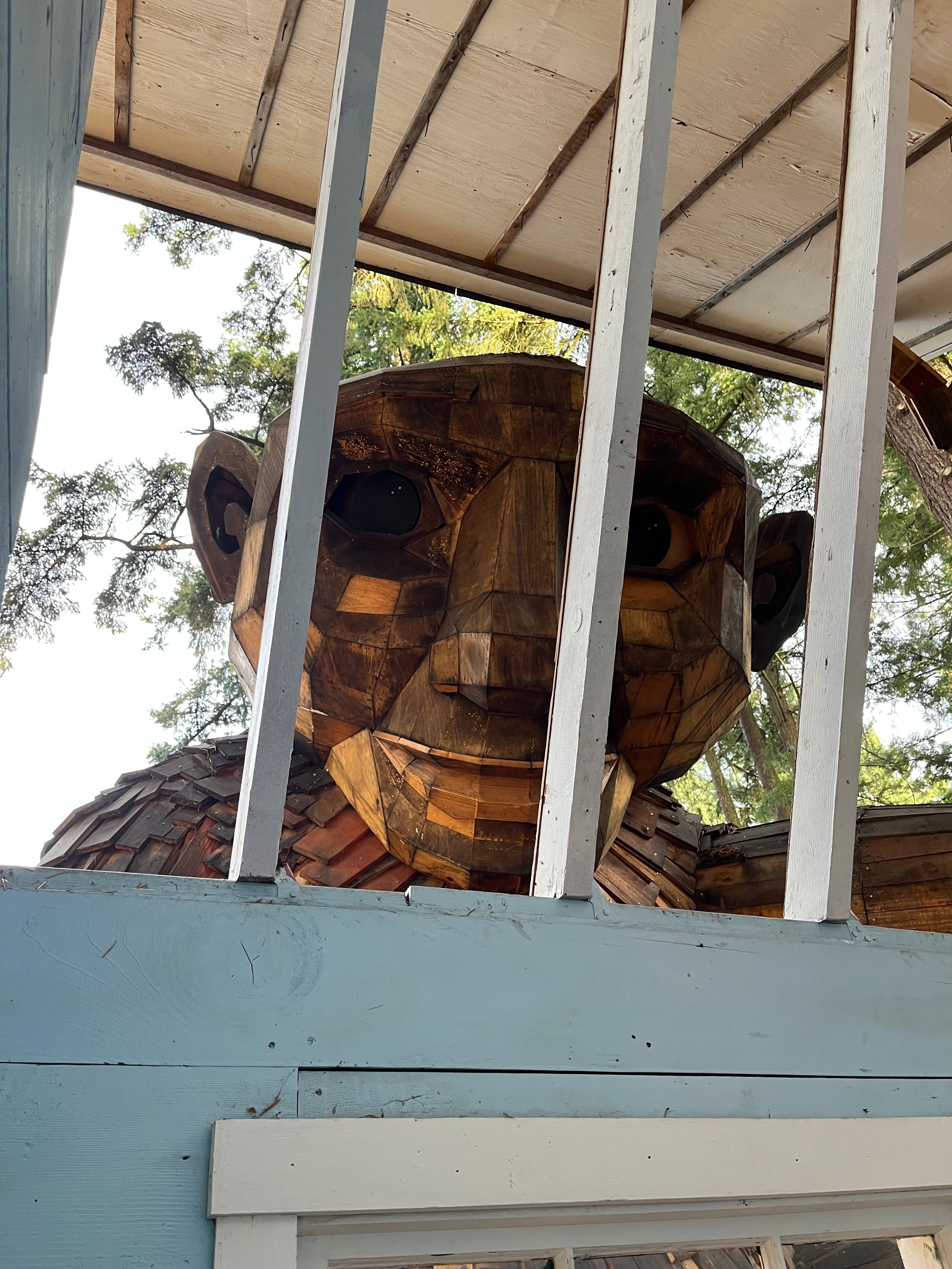 Face of a large wooden troll seen from inside the house. 