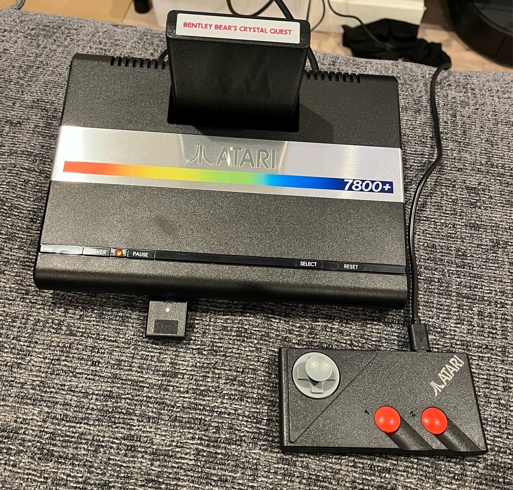 Atari 7800+ console with Bentley Bear's Crystal Quest cartridge inserted and game pad next to it. 